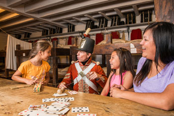 Trois enfants jouent aux cartes avec un interprète habillé en soldat britannique.