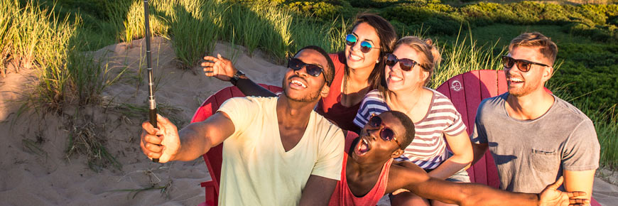 Five friends sitting on the Red Chairs smile for a selfie in the dunes