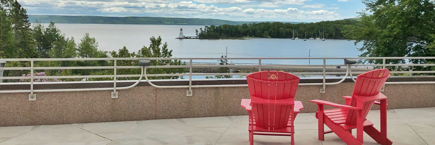 Two red chairs on a terrace in front of Bras d´Or Lake.