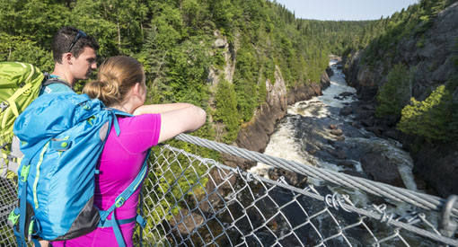 Des visiteurs admirent le paysage à partir du pont suspendu de la rivière White, près des chutes Chigamiwinigu.