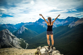 A young woman enjoys the peak of Sulphur Skyline with her arms outstretched