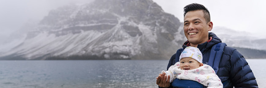 Man holding baby, poses in front of Bow Lake in the fall