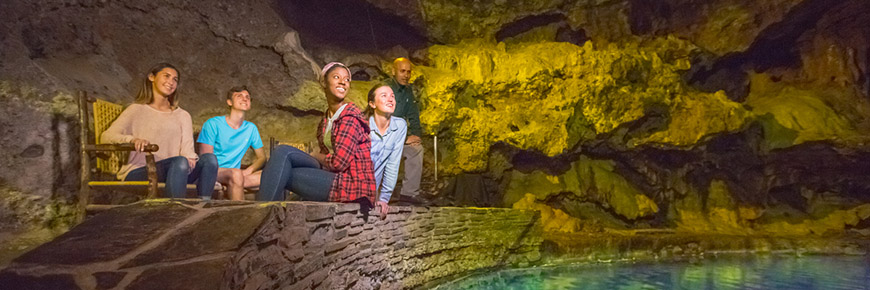 Des visiteurs assis à côté des eaux thermales turquoise dans la grotte Cave and Basin
