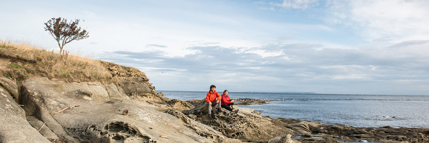 Un couple sur le littoral de la pointe East de l’île Saturna profite d’une vue panoramique sur l’océan