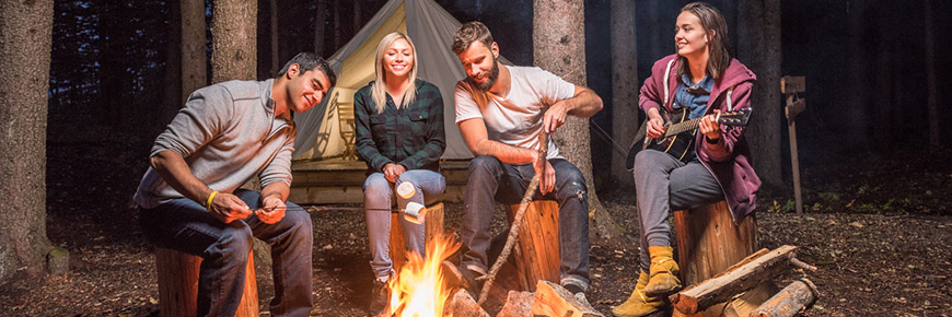 Des amis profitent de bons moments autour d'un feu de camp à proximité des tentes de trappeurs