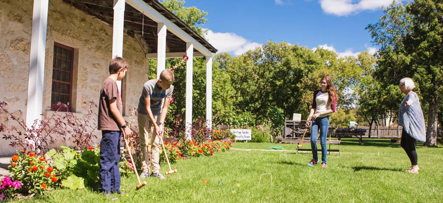 Youth playing croquet on the grounds of St. Andrew's Rectory