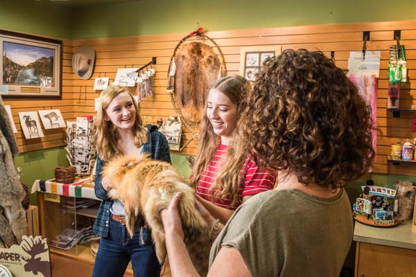 A family checks out a fur inside the Visitor Centre Trading Post gift shop at Rocky Mountain House National Historic Site.