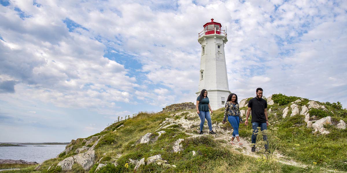 Trois visiteurs sur le sentier du Phare-de-Louisbourg, emplacement du premier phare au Canada (1734). Lieu historique national de la Forteresse-de-Louisbourg.
