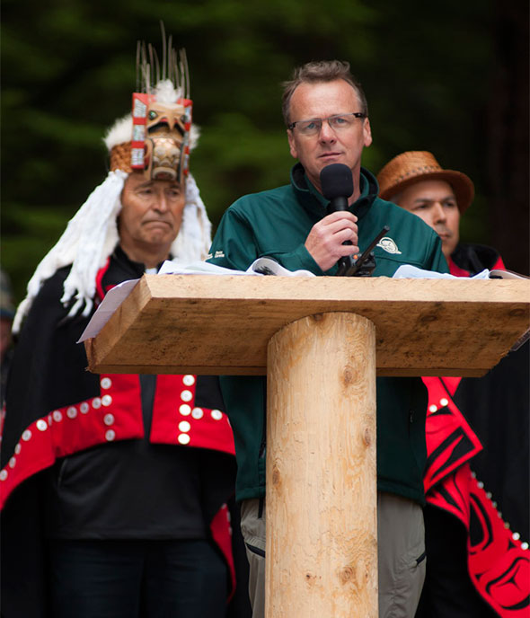 Parks Canada chief executive officer Alan Latourelle, flanked by hereditary chief Gidkun Reg Young (left) and Haida president Peter Lantin (right), addresses the crowd