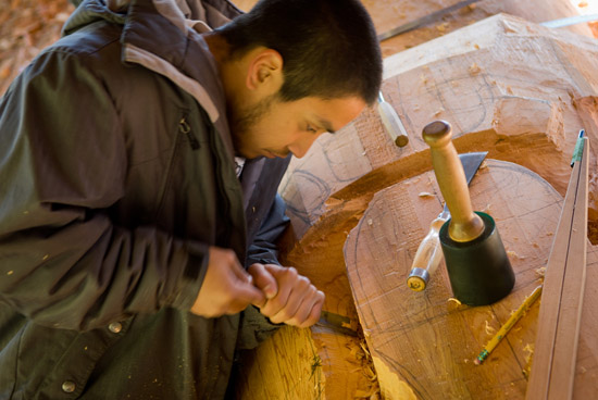 Carving assistant Tyler York carves out the major forms on the pole.