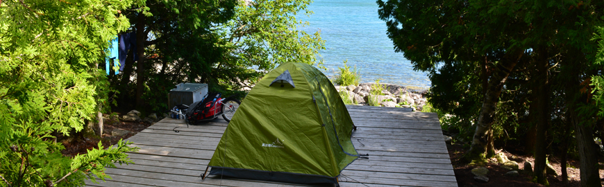 A tent on a wood platform overlooking the shoreline.