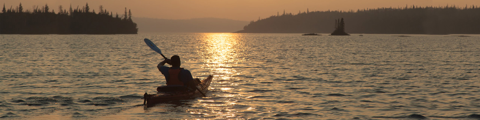 Une personne sur un kayak au coucher du soleil sur le lac Supérieur.