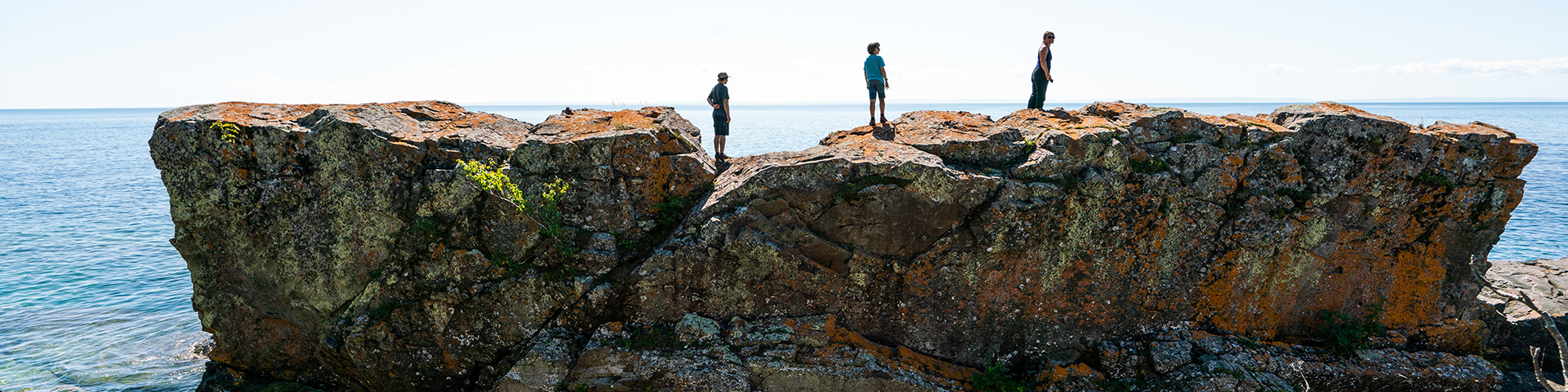 Three people standing on a large rock.