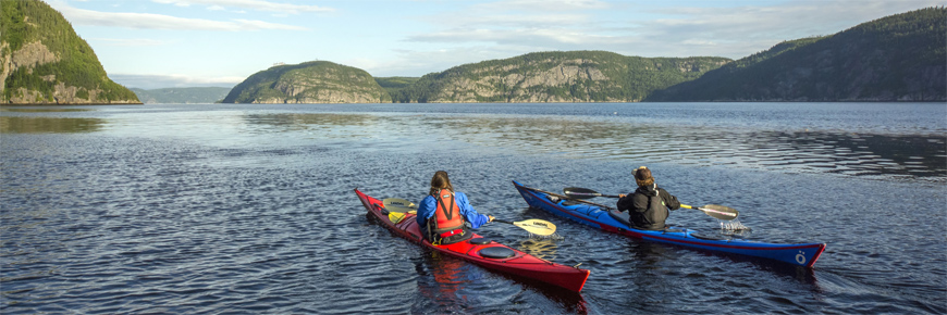 Un couple de visiteurs en kayaks pagayant allègrement sur la rivière Saguenay.