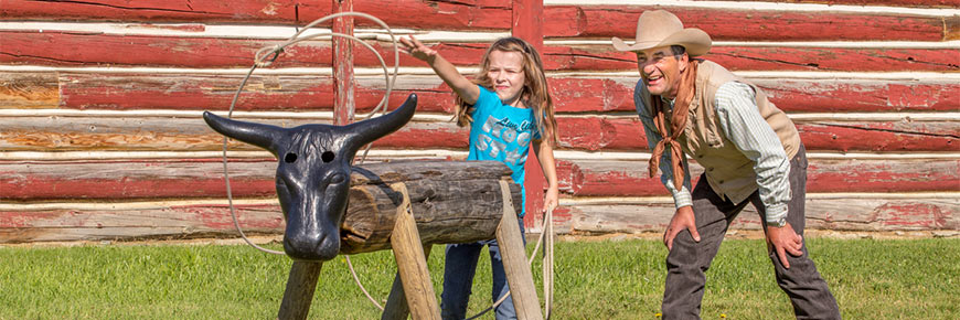 A girl tries roping a replica steer at Bar U Ranch National Historic Site