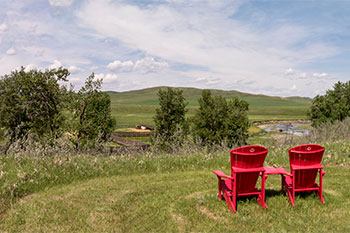 Two red chairs next to one of the walking trails at Bar U Ranch