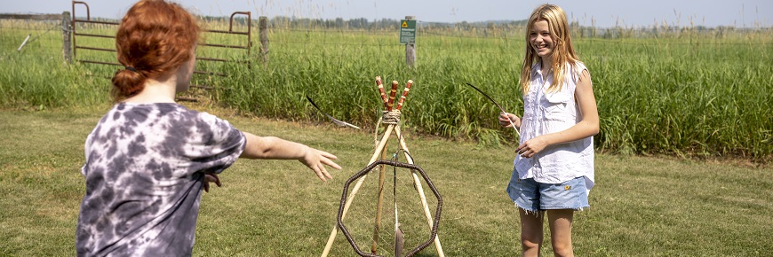 Two children playing a game of hoop and dart in a field