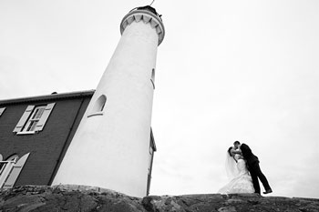 Photo de mariage en noir et blanc d’époux s’embrassant près du phare de Fisgard.
