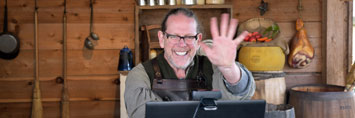 Interpreter smiling and waving his hand at the webcam.