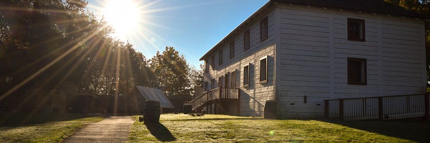 Le soleil brille de derrière la Grande Maison du fort Langley