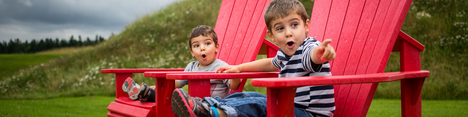 Two young boys with a look of amazement sitting on Parks Canada's red chairs