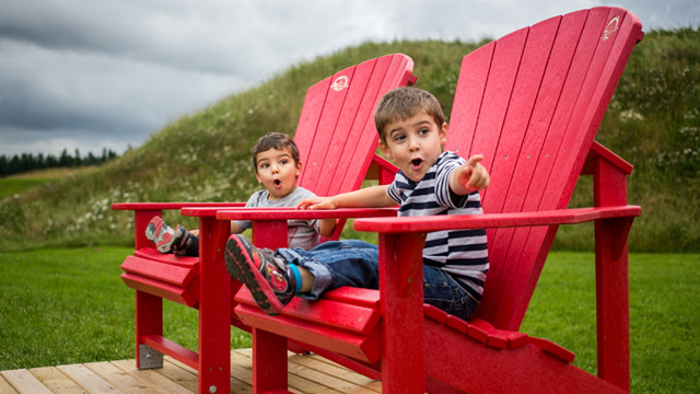 Deux garçons assis sur des chaises rouges au Fort Beauséjour, avec un regard émerveillé.
