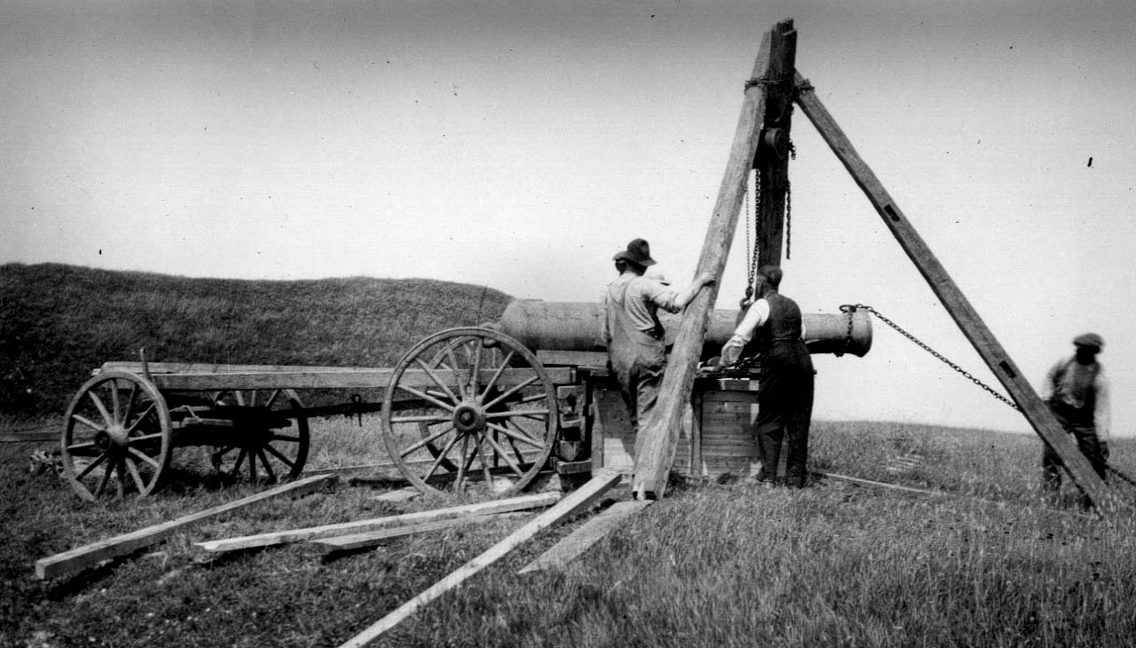 Three men moving a cannon