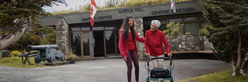 two people, one with a mobility device, walking away from the visitor centre