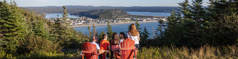 une famille assise sur des chaises rouges surplombant une communauté côtière