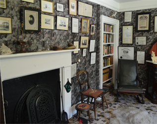 inside a grey room with a fireplace and many framed pictures on the walls