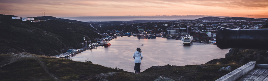 a woman overlooking the city if St. John's at sunset