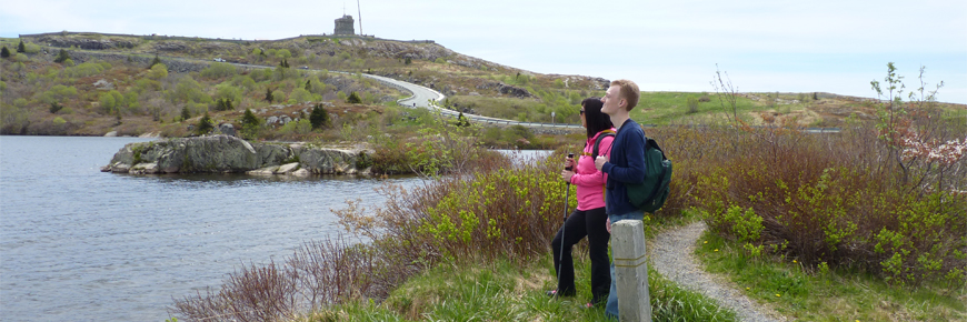 a man and a woman overlooking a pond with Cabot Tower in the background