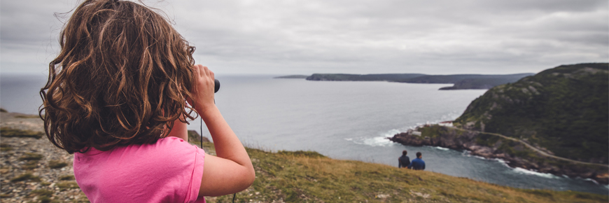 Girl looking at the coast through binoculars