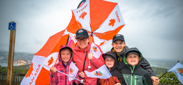 une famille de cinq personnes tenant des drapeaux canadiens et des parapluies du Canada