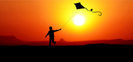 a silhouette of a child flying a kite at sunset