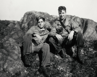 black and white photo of two soldiers sitting on the rocks