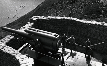 Black and white photo of 3 soldiers loading a cannon