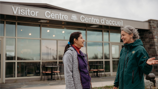 a Parks Canada employee talking to an individuals outside of the visitor centre