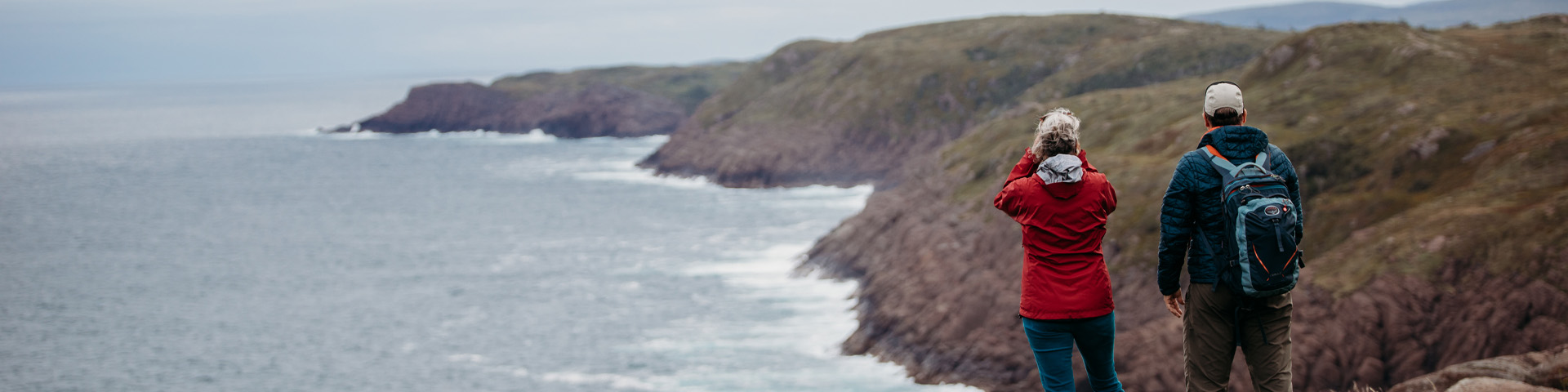 deux personnes debout sur un chemin en haut d'une falaise surplombant un sentier côtier