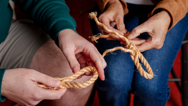 close-up of hands weaving rope.