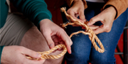 a close-up of two sets of hands splicing rope