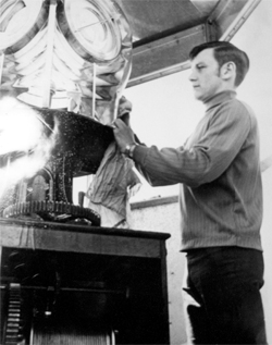 black and white image of a man cleaning a light mechanism