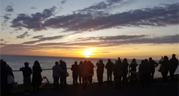 un groupe de personnes regardant un lever de soleil sur l'océan
