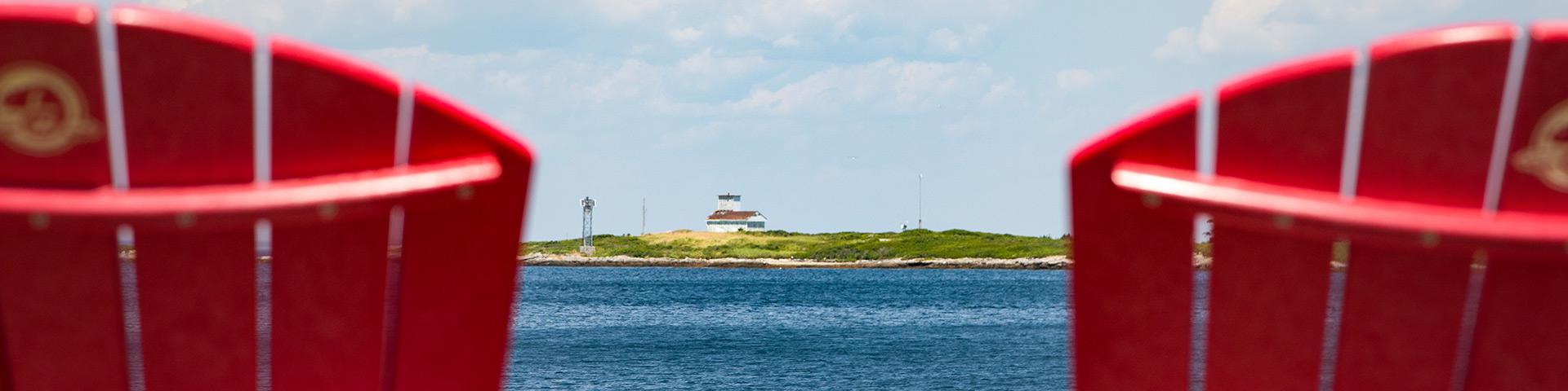 A view of Canso Island in the distance between two red chairs