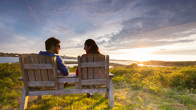 Un homme et une femme, assis sur des chaises en bois pendant que le soleil se couche