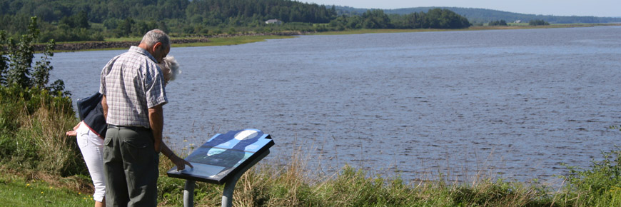 A couple reading an information plaque overlooking the Annapolis River. 