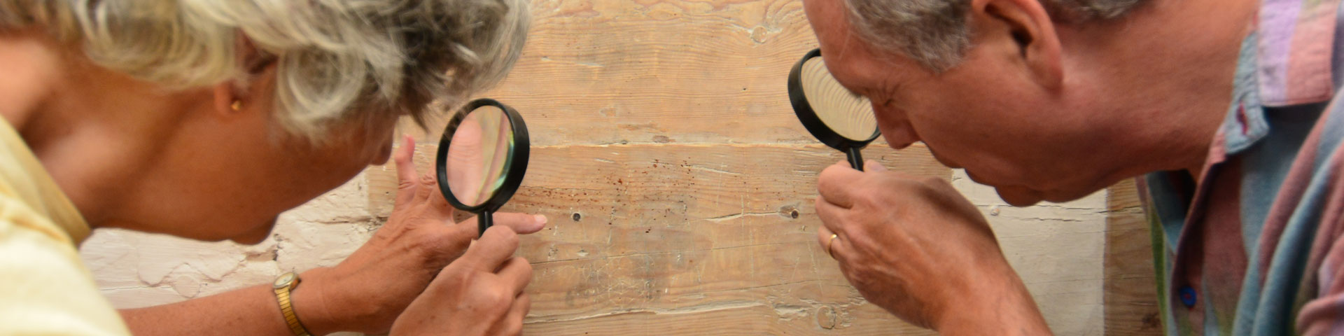 Visitors read historical graffiti with a magnifying glass. 