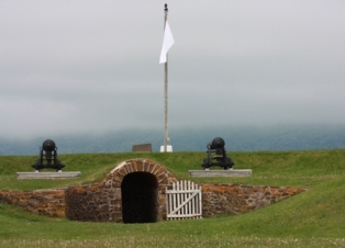 Vue horizontale du trou noir flanqué de deux canons avec un drapeau en arrière-plan.