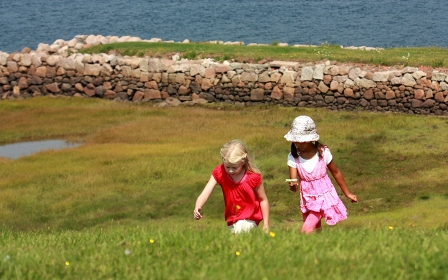 Deux enfants marchent sur le sentier périphérique, un mur de pierre est en arrière-plan.