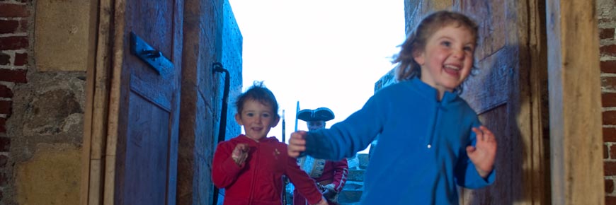 Two young visitors smiling and running through the doors at Fort Anne National Historic Site.
